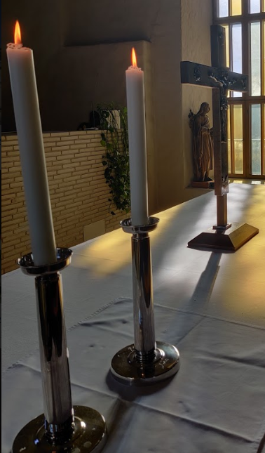 Kuvassa on kaksi valkoista kynttilää kynttilänjalkoihin kiinnitettynä Pyhän Mikaelin kirkon alttaripöydällä.