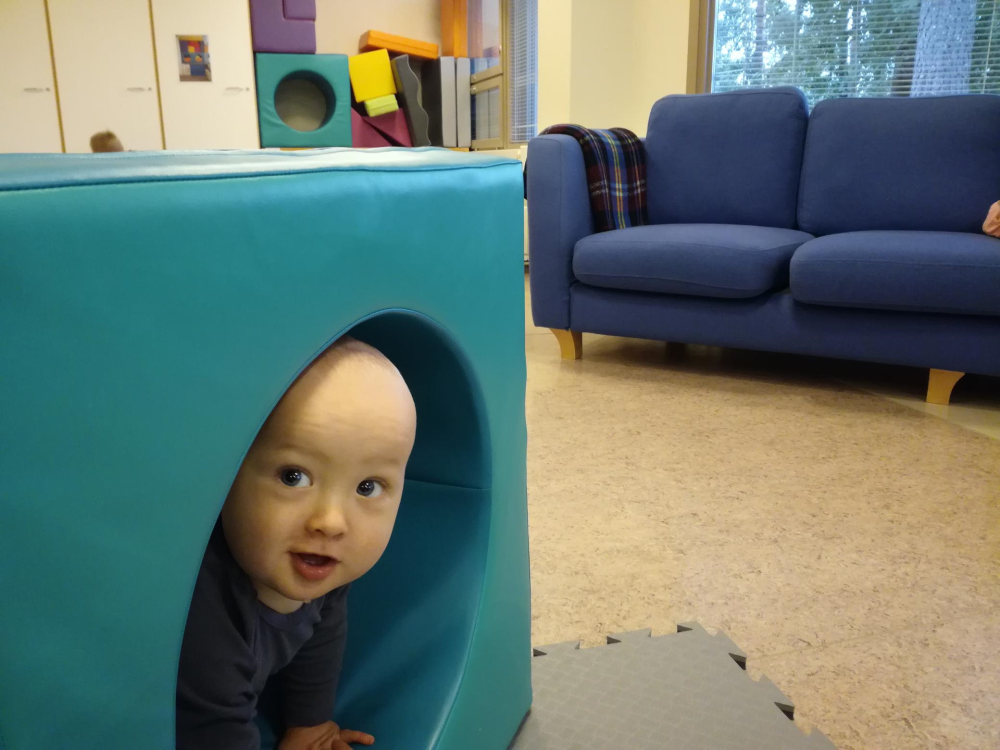 Hymyilevä vauva kurkistaa suuren tunnelipalikan sisältä temppuradalla.