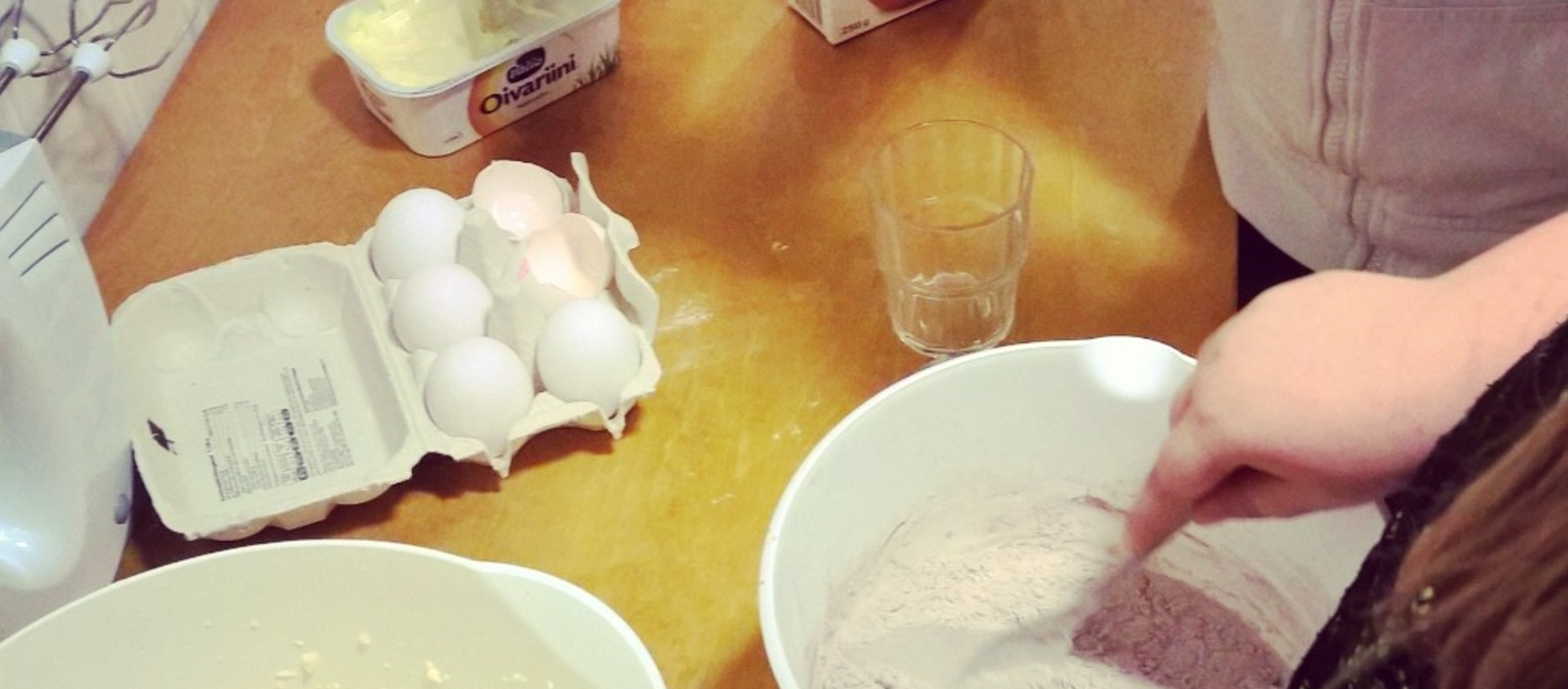 lapsen käsi sekoittaa taikinaa lusikalla pöydällä kananmunia sähkövatkain jauhokulho lasi margariini