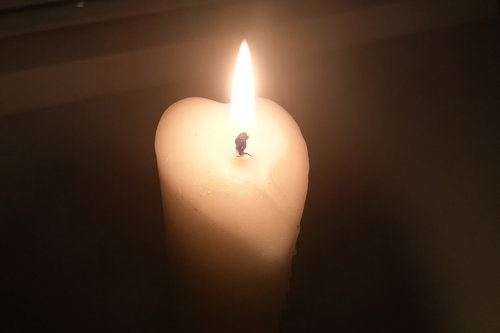 Sydämen muotoinen valkoinen kynttilä pimeydessä.