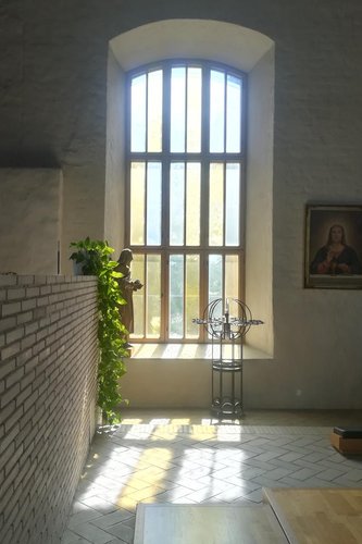 Valo heijastuu Kirkkonummen kirkon ikkunan kautta lattialle. Ristikkoikkunan kautta muodostuu risti lattiaan.