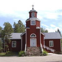 Puiden ympäröimä punaiseksi maalattu puinen ristikirkko, jonka pääoven edessä korkeat kiviportaat. Kellotorni kohoaa suoraan pääoven yläpuolella. 