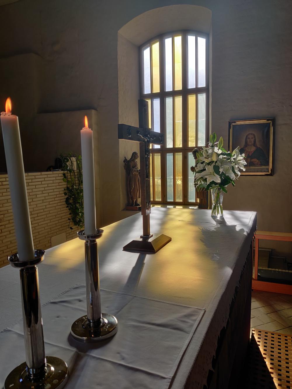 Kirkkonummen Pyhän Mikaelin kirkon alttaripöytä, sen kynttilät, krusifiksi ja kukat.