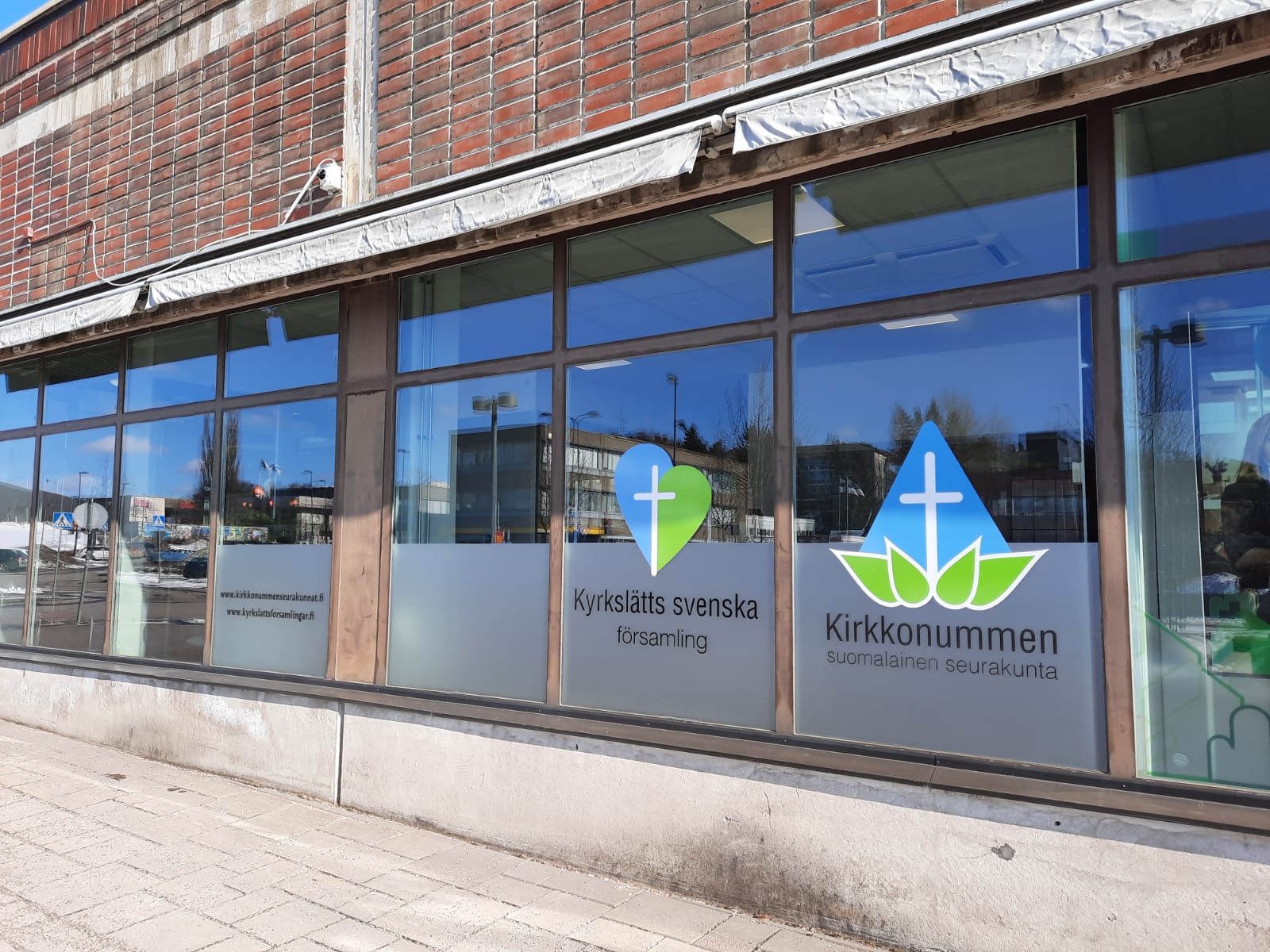 Kirkkotallintie 2 Kirkkoherranvirastojen julkisivu Ervastientien suunnasta. Ikkunoissa seurakuntien sinivihreät logot.