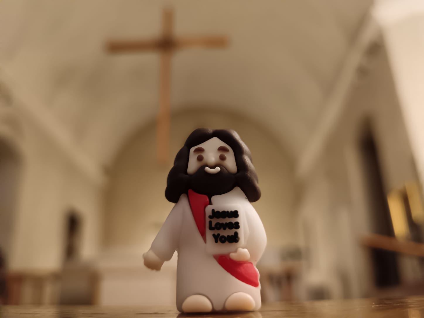 Pieni Jeesus pitää kirkossa kylttiä, jossa lukee ''Jesus loves you''.
